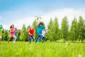 A group of kids playing in a green meadow on a sunny day.