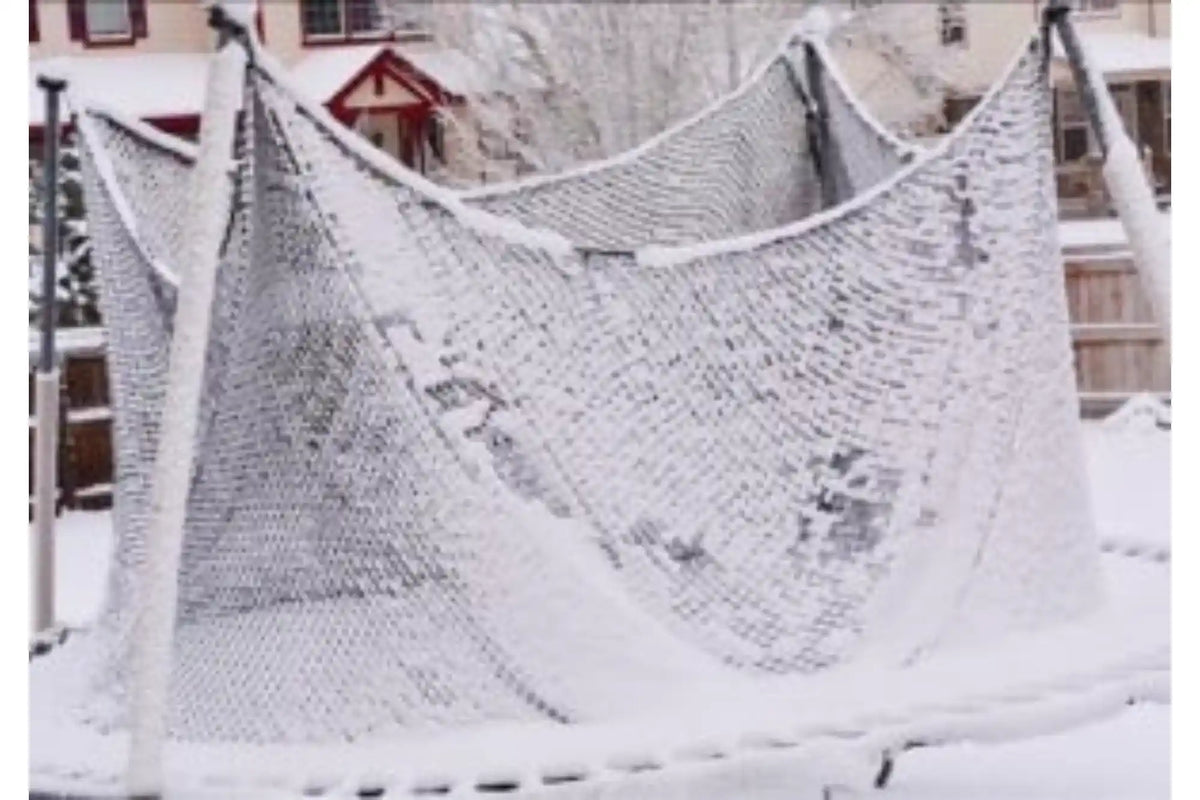 Snow-covered trampoline with a safety enclosure sagging under the weight of accumulated snow during winter weather.