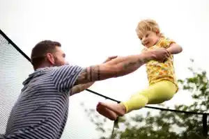 A man playing with a little girl on a trampoline