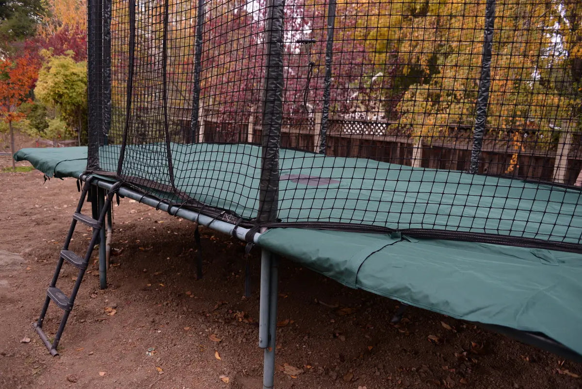 A side view of a rectangular cover on an AlleyOOP trampoline. The JumpSport trampoline weather cover guards your trampoline from harmful UV rays and keeps the temperature cooler on the mat! Protect your investment now.