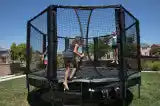 A girl climbing into a padded trampoline enclosure. These trampoline arena pads are a great addition for the budding extreme athlete. Extra padding for your JumpSport trampoline that makes it safer!